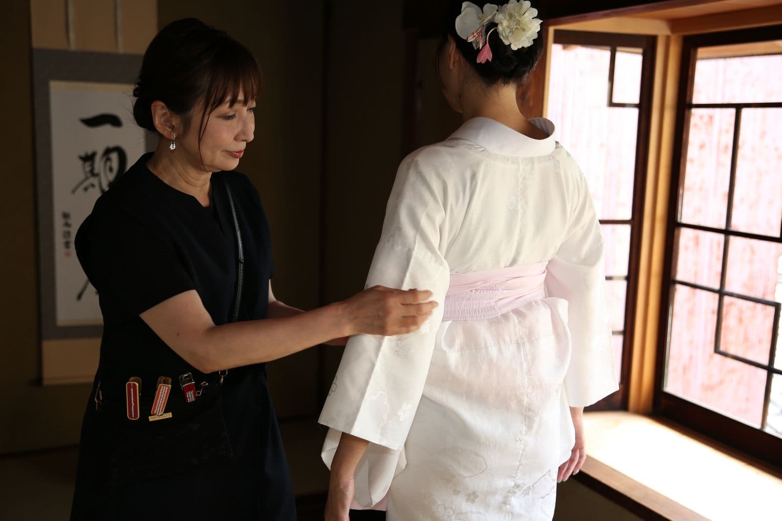 Instructor beginning to dress a guest in kimono
